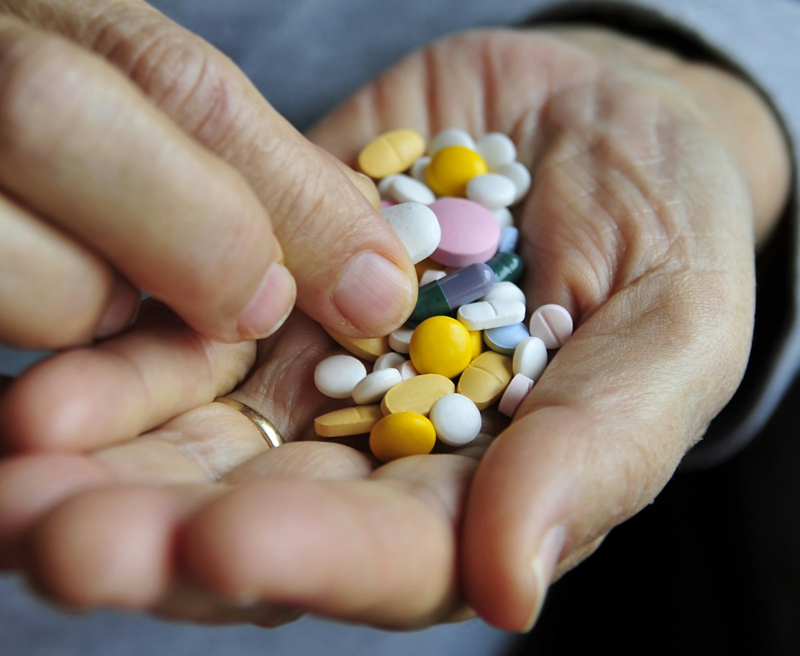 Manos sosteniendo un puñado de pastillas de colores