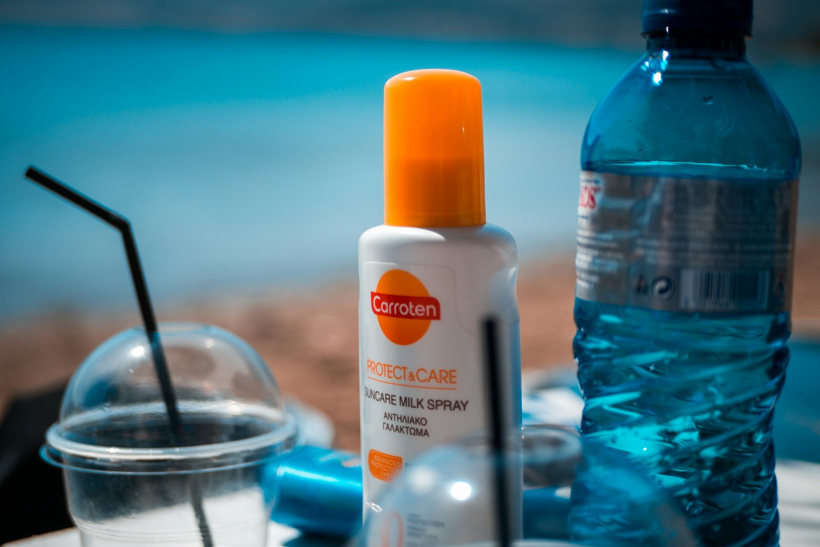 Bote de protector solar blanco y naranja sobre mesa azul con luz cálida